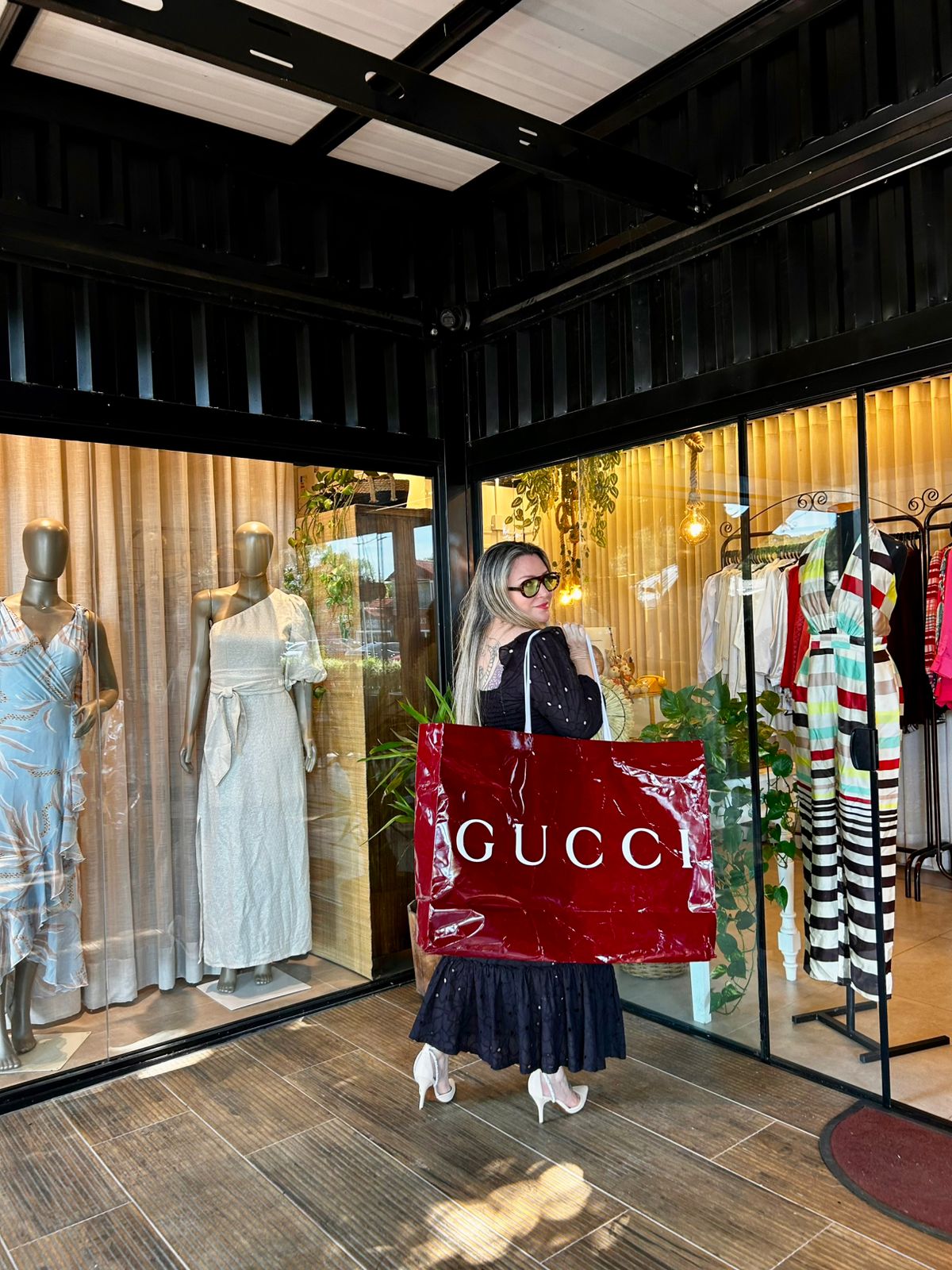 Fê Bassi em frente à vitrine com peças de grife