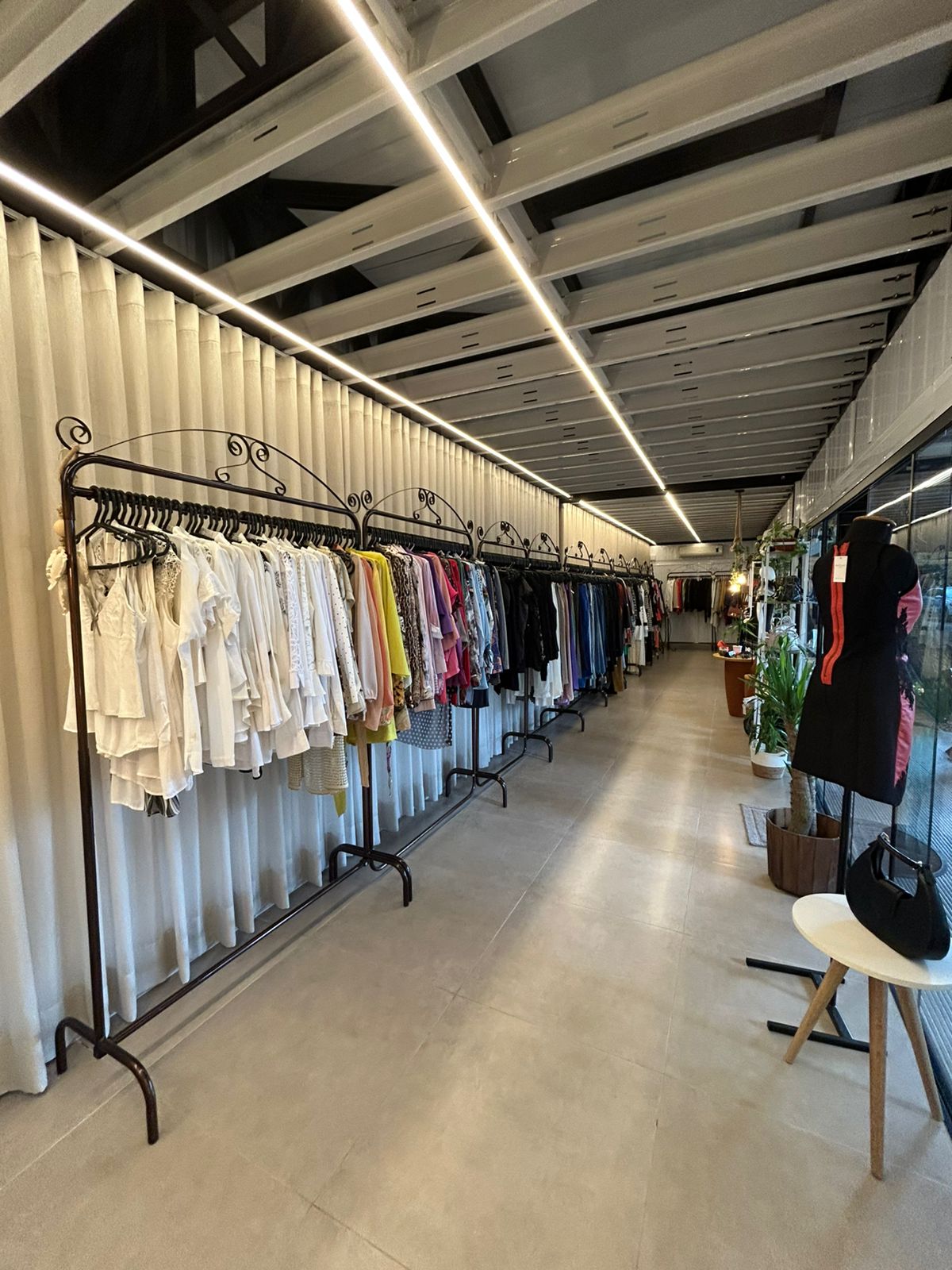 Interior do brechó com araras de roupas organizadas